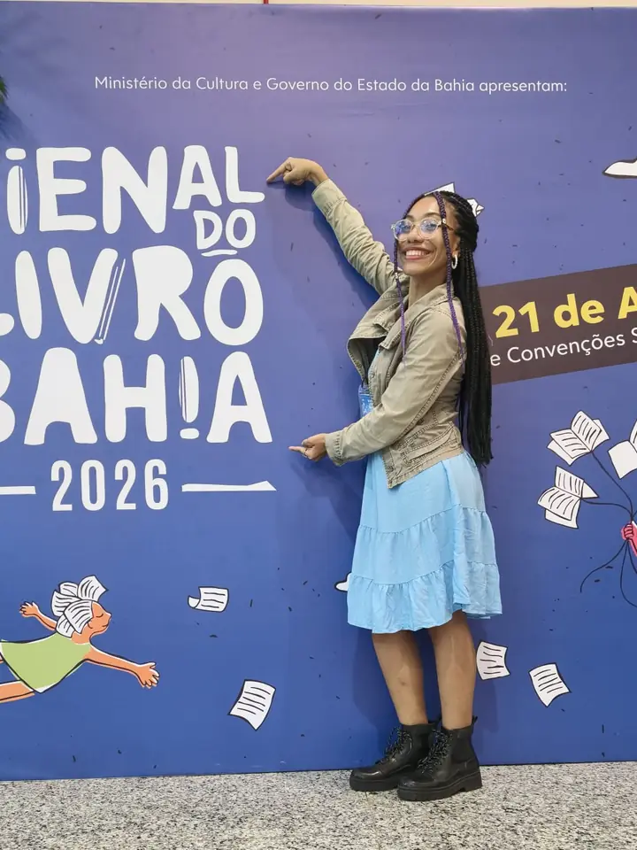 Júlia apontando para o painel da Bienal do Livro Bahia 2026