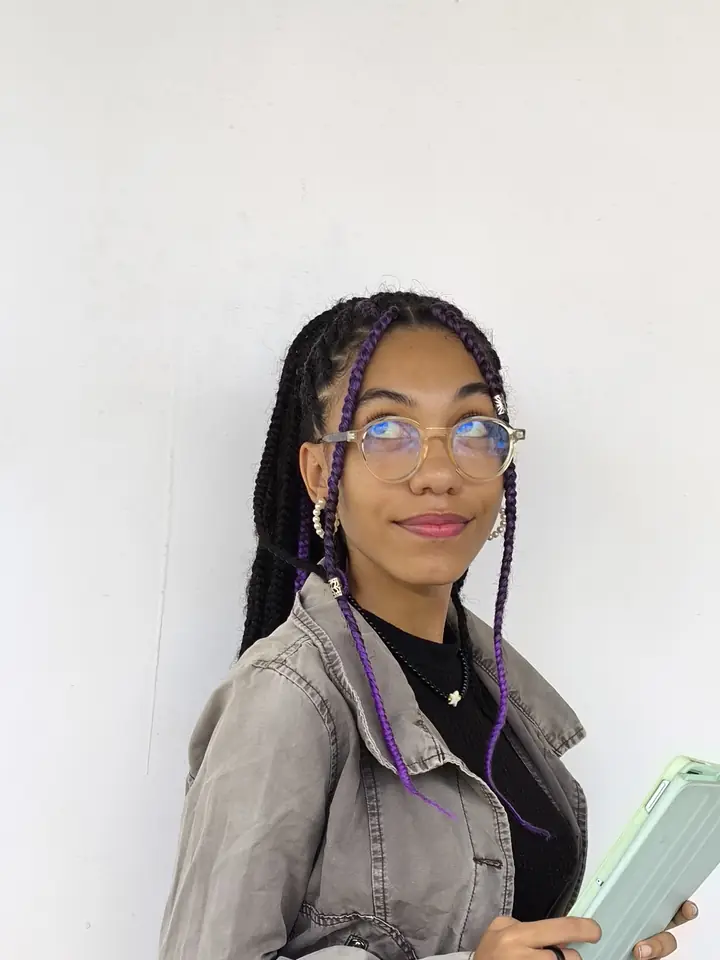 Júlia de jaqueta jeans segurando um livro na Bienal BA